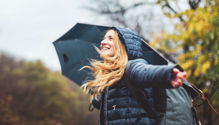 vrouw loopt buiten in de regen met paraplu in de herfst