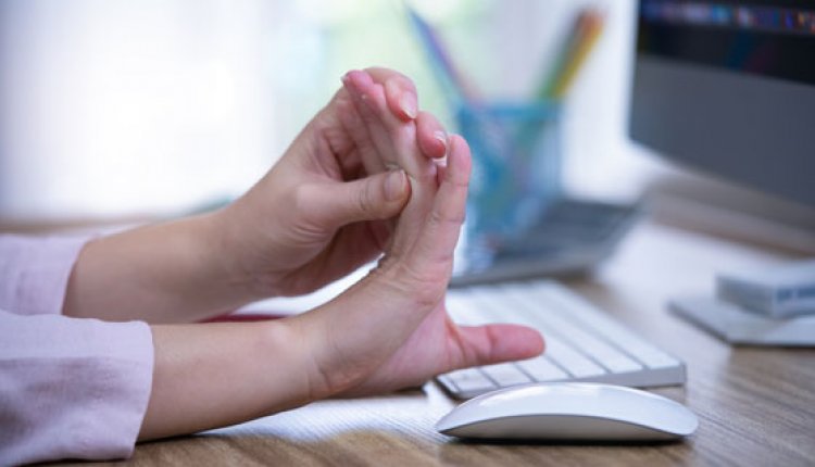 Vrouw achter bureau strekt haar vingers