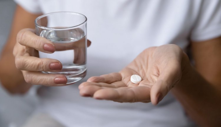 vrouw met glas water en paracetamol in de hand