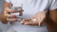 vrouw met glas water en paracetamol in de hand