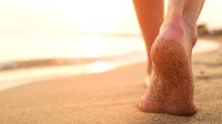 Vrouw loopt met blote voeten op het strand
