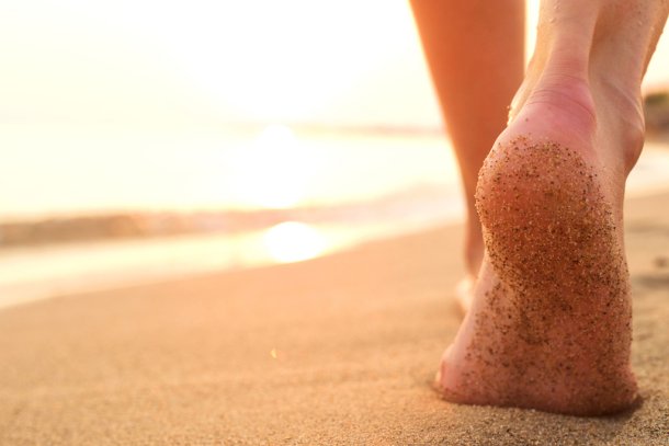 Vrouw loopt met blote voeten op het strand
