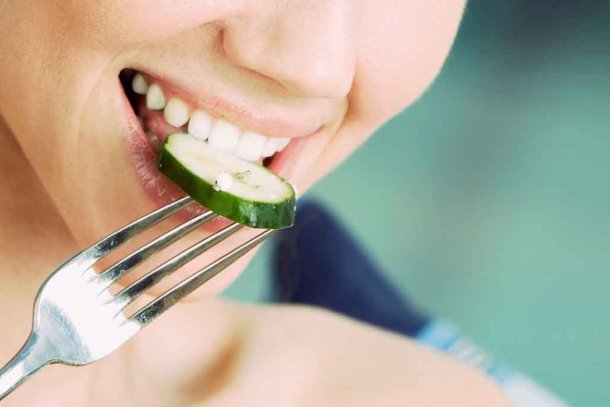 Vrouw eet plakje komkommer met een vork