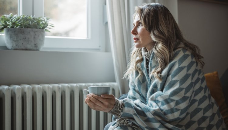 Vrouw voor verwarming in kleed met kop warme drank