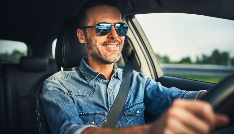 Man met zonnebril op achter het stuur van een auto