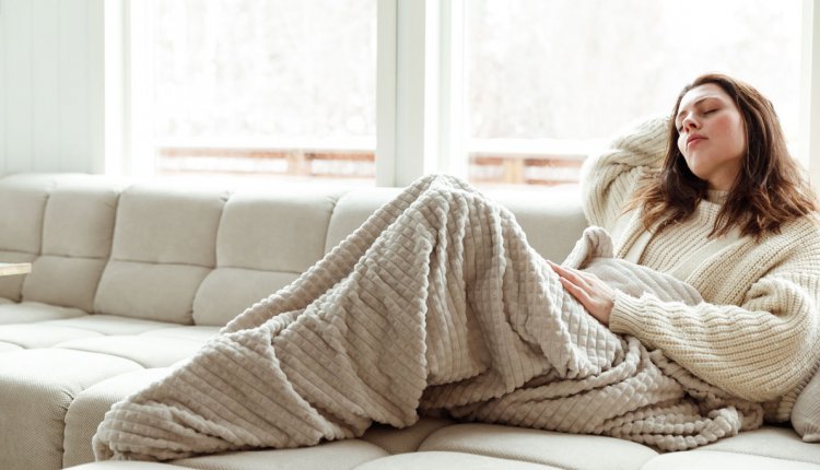 Vrouw met menstruatieklachten op de bank