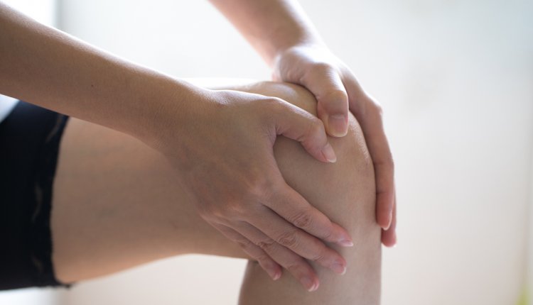 vrouw voelt aan knie met hand