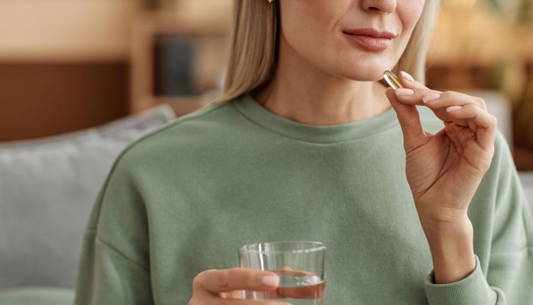 Vrouw neemt supplement in met een glas water
