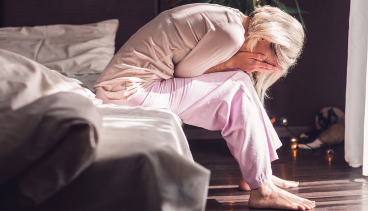 Vrouw zit met de handen in het haar op bed