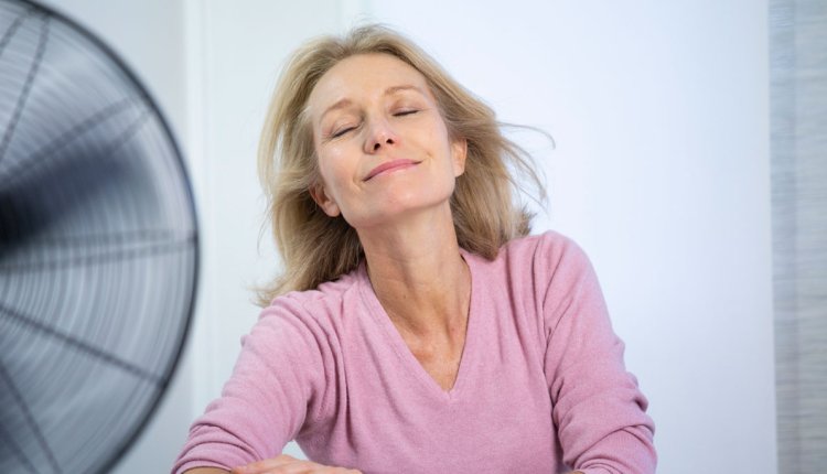 Vrouw zit voor een ventilator omdat ze het warm heeft