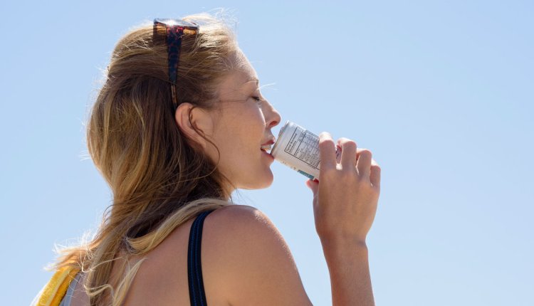 Vrouw drinkt uit een blikje frisdrank met warm weer