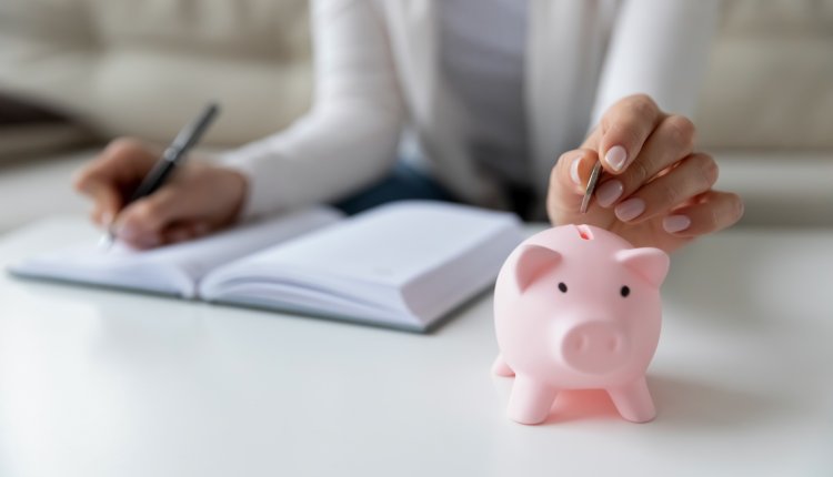 Vrouw houdt administratie bij en stopt geld in een spaarvarken