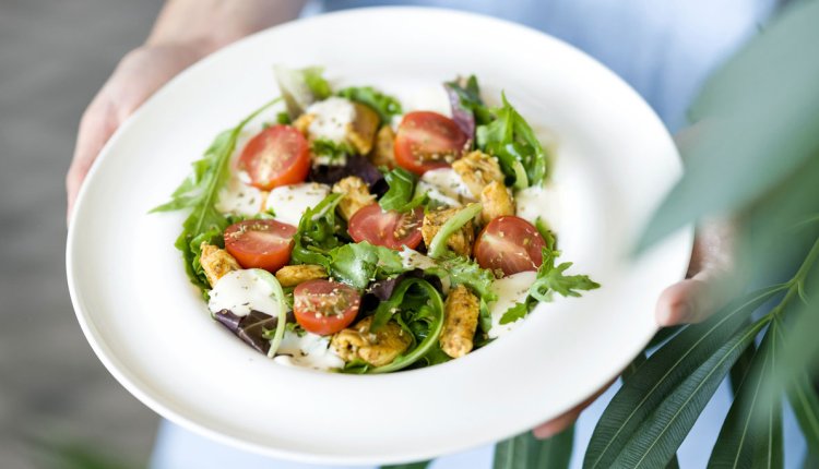 Wit bord met een salade met tomaat, mozzarella en meer