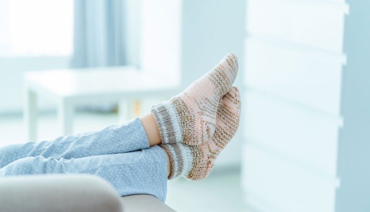 Vrouw op de bank met voeten in warme dikke sokken