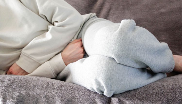 Vrouw ligt op bank met pijn aan het bekken