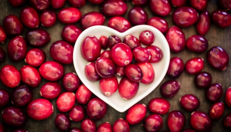 Cranberries in een schaaltje op een houten plank met daarop ook de besjes