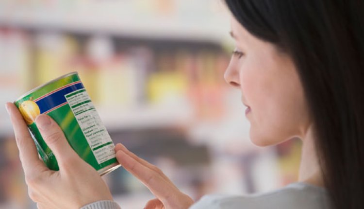 Vrouw leest in de supermarkt etiket op de verpakking van een blik