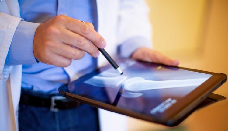 man met ipad met foto van artrose