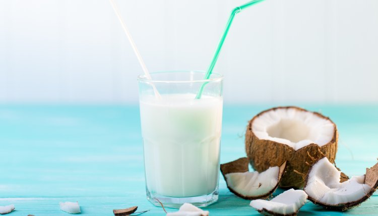 Glas kokosmelk en een kokosnoot in stukken