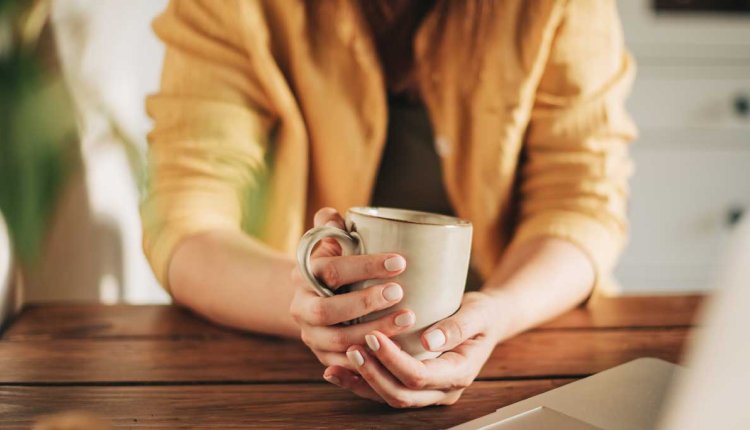 vrouw drinkt koffie achter computer