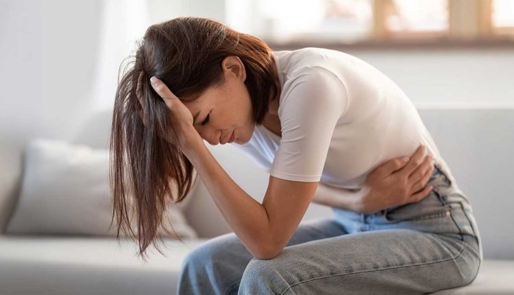 Vrouw met buikpijn op de bank