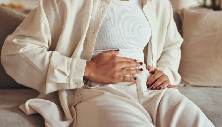 Vrouw met hand op haar buik omdat ze daar pijn heeft