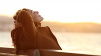 Vrouw in de zon op een bankje in de herfst