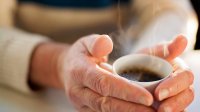 Vrouw warmt handen aan koffie