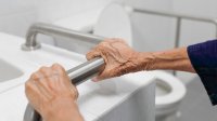 vrouw houdt handgreep vast bij wc
