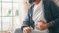 Man met hand op zijn pijnlijke buik