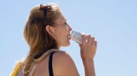 Vrouw drinkt uit een blikje frisdrank met warm weer