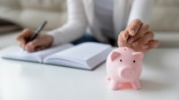 Vrouw houdt administratie bij en stopt geld in een spaarvarken