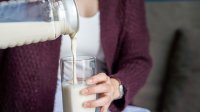 Vrouw schenkt havermelk in een groot glas