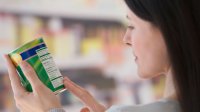 Vrouw leest in de supermarkt etiket op de verpakking van een blik