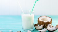 Glas kokosmelk en een kokosnoot in stukken