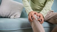 man net pijnlijke knie op de bank