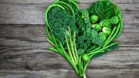 Groene groenten in een hartvorm neergelegd op een houten plank