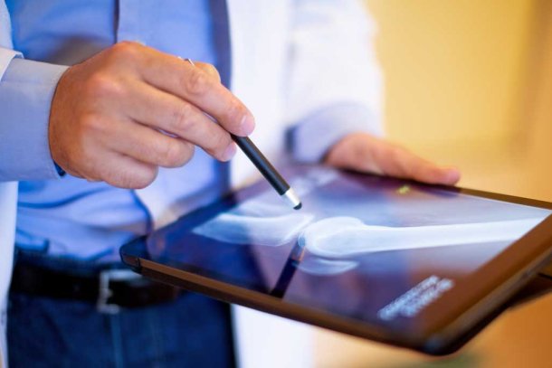 man met ipad met foto van artrose
