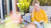 Vrouw zit op terras en eet blauwe bessen