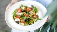 Wit bord met een salade met tomaat, mozzarella en meer