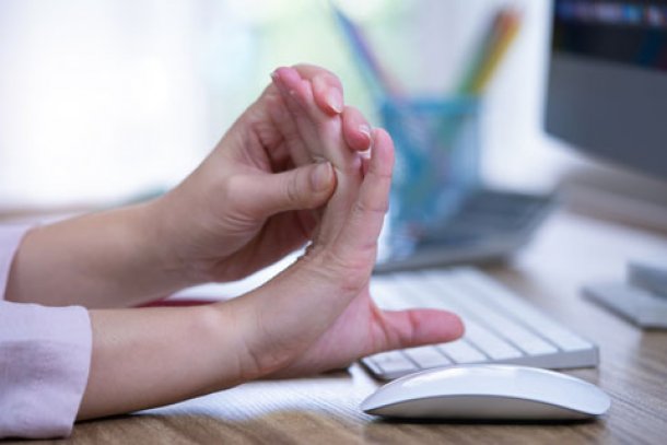Vrouw achter bureau strekt haar vingers