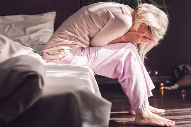 Vrouw zit met de handen in het haar op bed