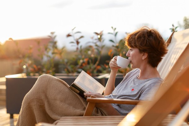 Vrouw drinkt een kop koffie in de ochtendzon