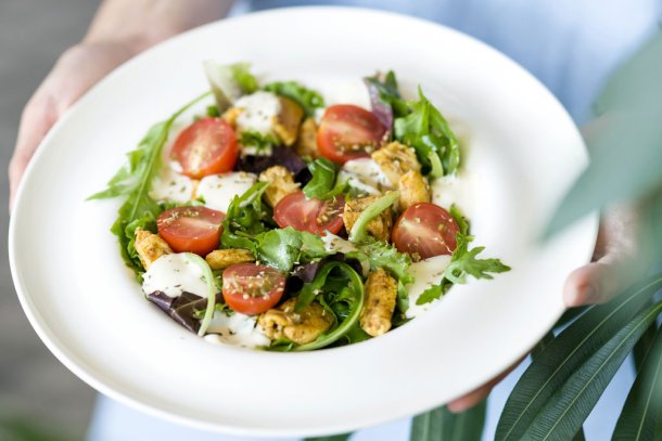 Wit bord met een salade met tomaat, mozzarella en meer
