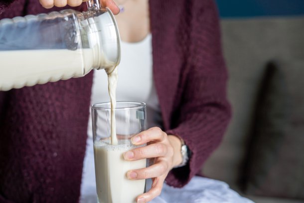 Vrouw schenkt havermelk in een groot glas