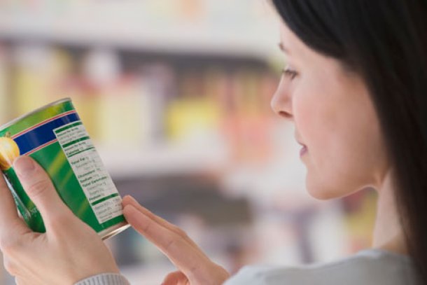 Vrouw leest in de supermarkt etiket op de verpakking van een blik