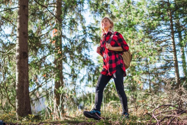 Vrouw loopt ontspannen door de bossen in het herfstzonnetje